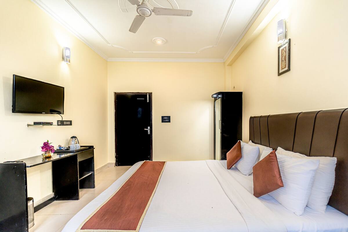 A hotel room with a bed, a television, a desk, and a door.