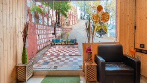 A room with a checkered floor, a green rug, a black leather sofa, and two side tables with vases. - Flutter Hotels & Resort (Lansdowne)