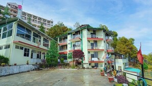 A multi-story hotel with balconies, a swimming pool, and a parking area. - Flutter Hotels & Resort (Lansdowne)