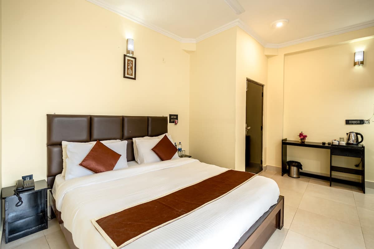 A hotel room with a large bed, a desk, and a chair.