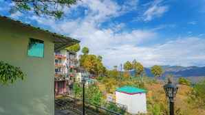 A hillside view with a building featuring balconies and a red roof. - Flutter Hotels & Resort (Lansdowne)
