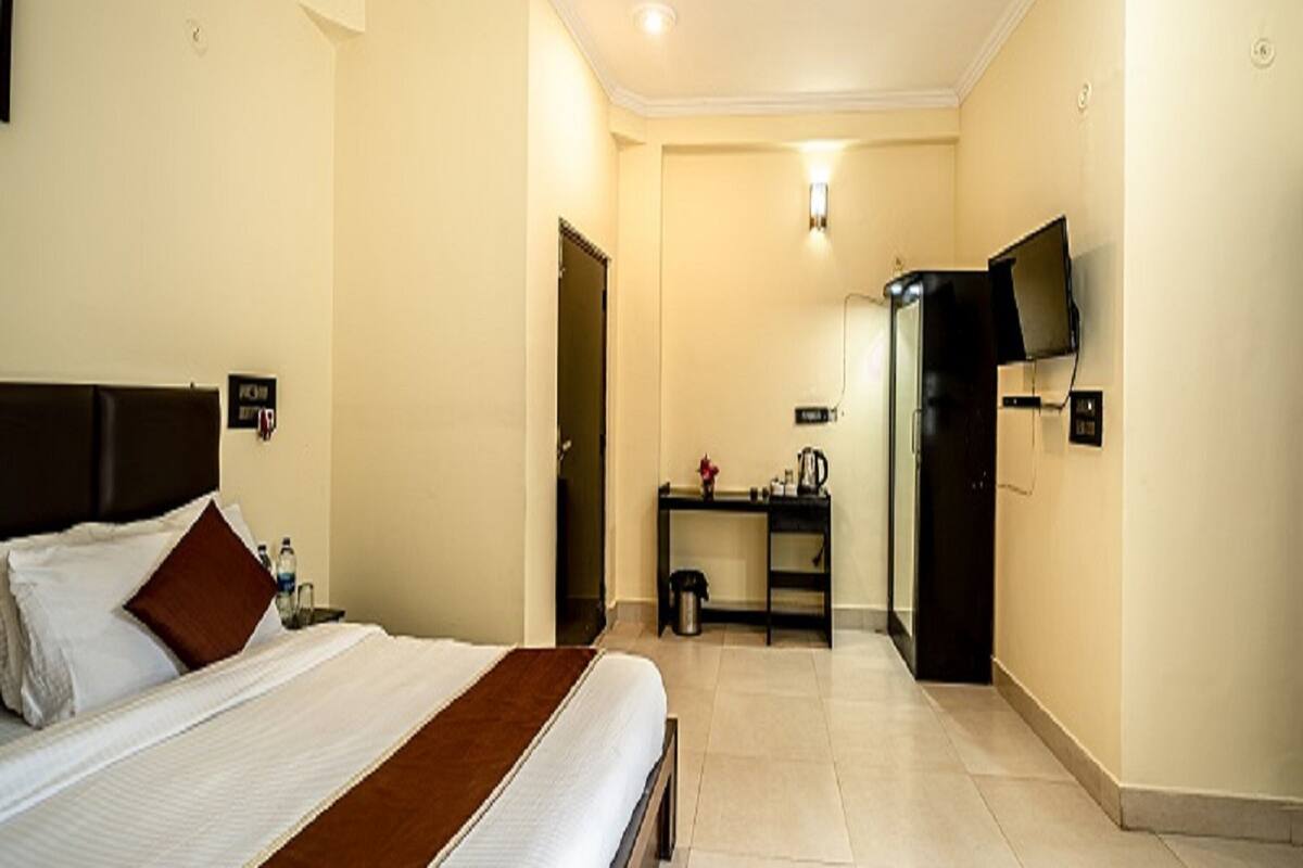 A hotel room with a bed, a desk, a television, and a bathroom.
