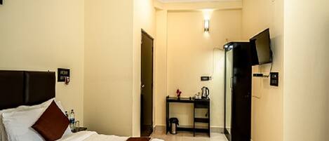 A hotel room with a bed, a desk, a television, and a bathroom.