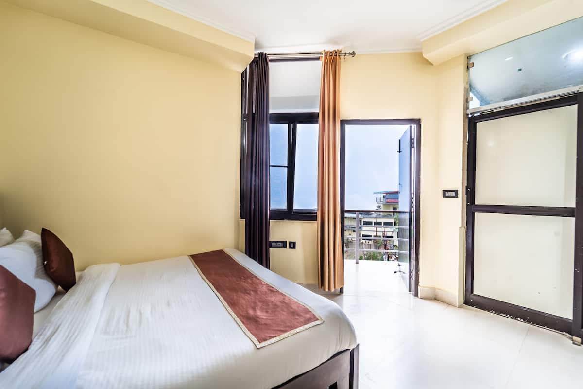 A hotel room with a bed, a view of the outside, and a balcony.