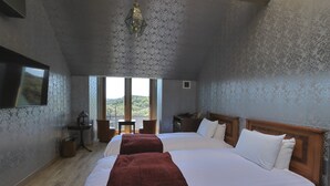 Une chambre avec deux lits, une télévision, une lampe, une chaise et une vue sur l’extérieur.