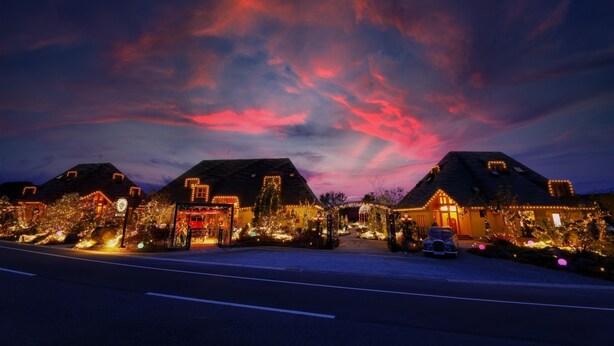 Une rangée de maisons décorées de guirlandes lumineuses de Noël, sous un ciel dégagé.