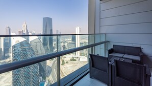 Un balcon avec vue sur la ville, un mobilier moderne et une balustrade en verre.