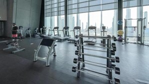 Une salle de sport équipée de machines de cardio, de matériel de musculation et de grandes fenêtres donnant sur la ville.