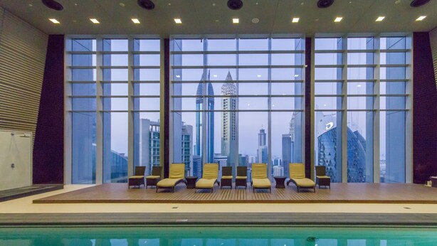 Un espace piscine offrant une vue sur les gratte-ciel de la ville grâce à de grandes fenêtres.