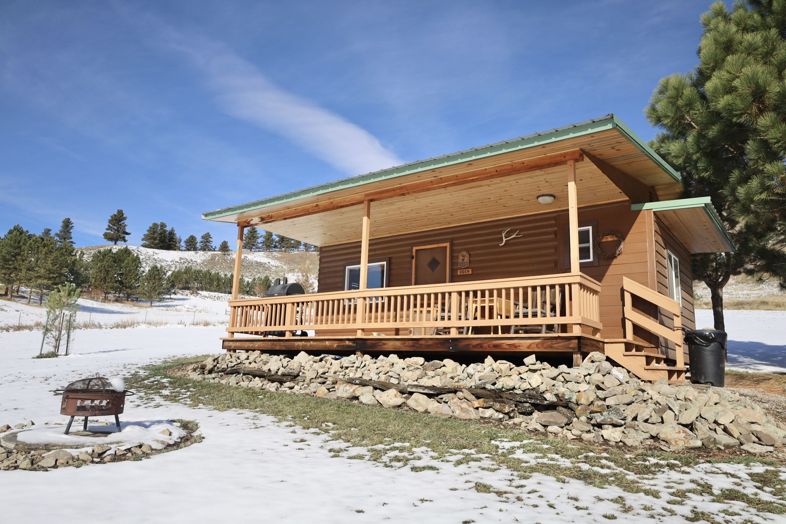 Une cabane en bois avec un porche, des fondations en pierre et un ciel dégagé.