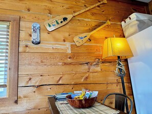 Cozy cabin-style room with a wooden paddle wall decoration, a table for dining or relaxation, and a warm lamp.
