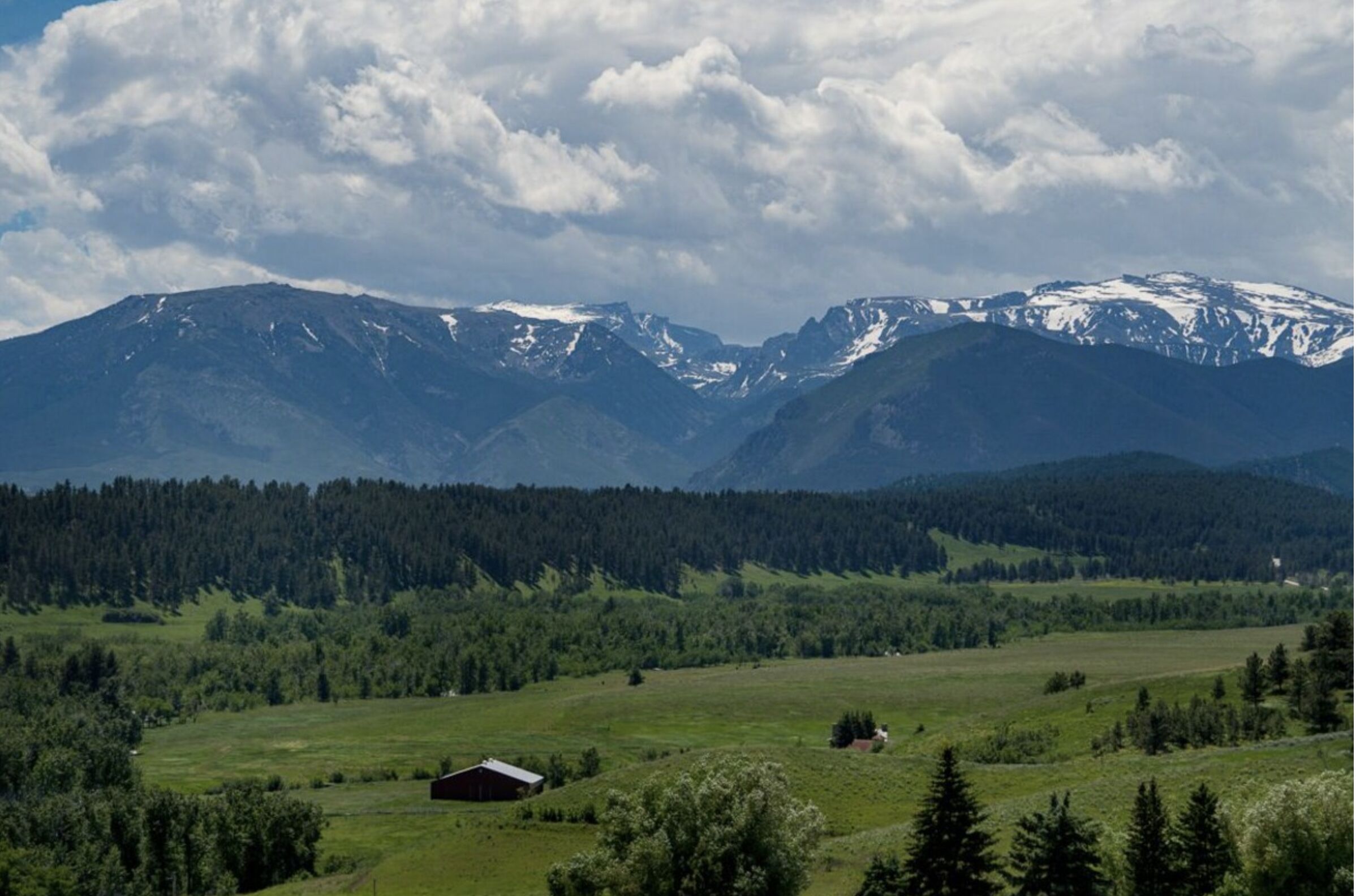 A mountainous landscape with a small building in a green field.