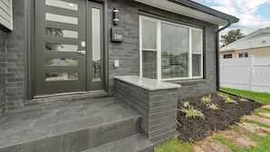 Een modern huis met een donkergrijze bakstenen gevel, een groot raam met witte zonwering, en een brievenbus met nummer 3801.