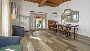 A dining area with a wooden table and chairs, a sofa, and a ceiling with exposed beams. - Fontesecca (Citta della Pieve)