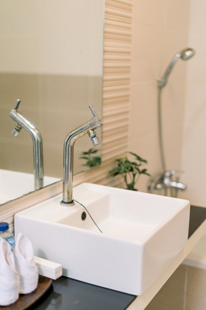 A bathroom with a white sink, two chrome faucets, and a handheld showerhead.