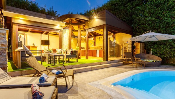 A modern outdoor living area with a pool, lounge chairs, and a covered patio.