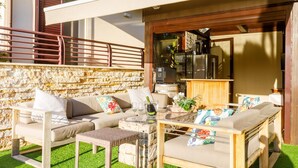 An outdoor seating area with a stone wall, a wooden deck, and a glass-top table.