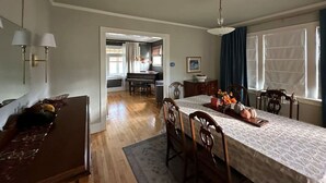 Un comedor con una mesa larga, sillas y un piano al fondo.