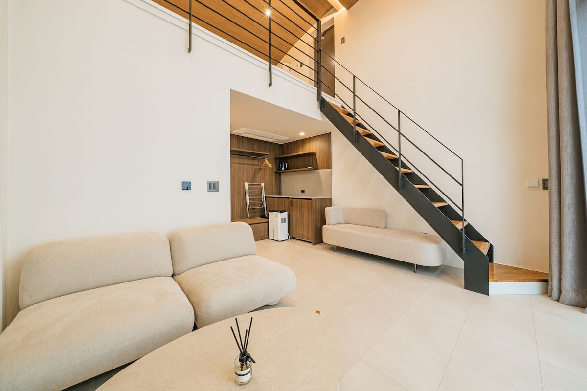 A modern living room with a sofa, a coffee table, and a staircase with a metal railing.