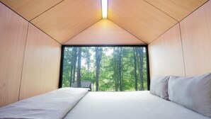 A bedroom with a large window, wooden walls, and a bed. - Bobocabin The Tavia Puncak (Megamendung)
