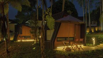 A modern resort with wooden cabins, outdoor seating, and ambient lighting.