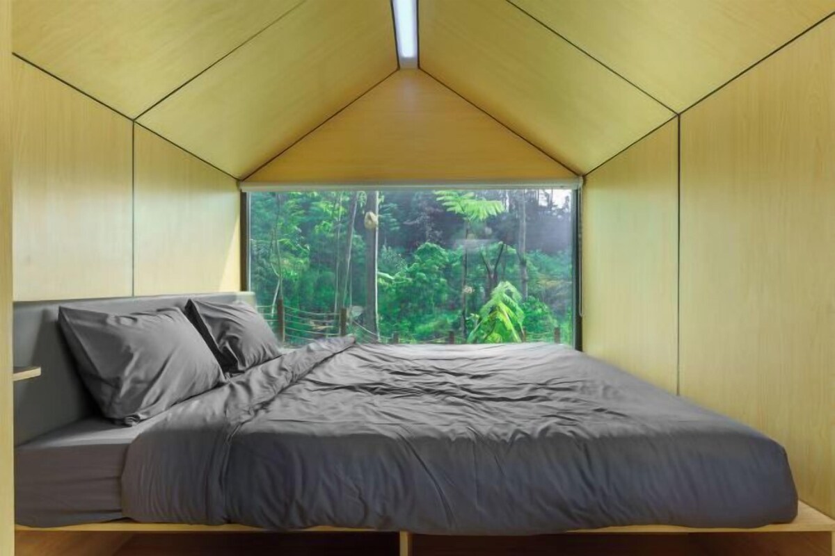 Une chambre à coucher avec un lit, une fenêtre et une vue sur la verdure.