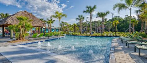 A swimming pool with lounge chairs and palm trees.