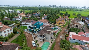 A residential area with houses, a swimming pool, and a road. - Villa Reverie 6 Bedroom Ultra Modern (Betalbatim)