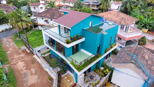 A two-story residential building with a blue exterior, a balcony with plants, and a small garden area. - Villa Reverie 6 Bedroom Ultra Modern (Betalbatim)