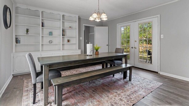 A dining area with a wooden table, benches, a chandelier, and a white shelving unit. - 15 Minutes from Downtown! Welcome to Woodbridge (Montgomery)