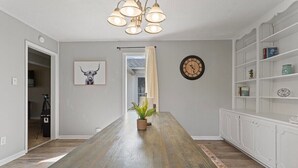 A spacious dining area with a long wooden table, a chandelier, a clock, and a bookshelf. - 15 Minutes from Downtown! Welcome to Woodbridge (Montgomery)