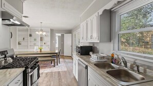 A modern kitchen with white cabinetry, a stainless steel sink, and a built-in stove. - 15 Minutes from Downtown! Welcome to Woodbridge (Montgomery)