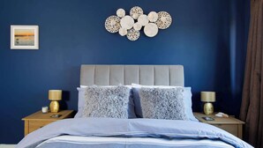 Un dormitorio con una cama, dos mesitas de noche, una obra de arte en la pared y un cuadro enmarcado.