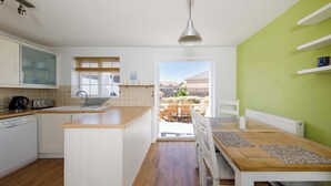 Una cocina con encimera de madera, armarios blancos y vistas a un patio exterior.