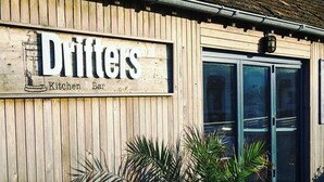 Un edificio de madera con un letrero que dice "Drifters Kitchen Bar".