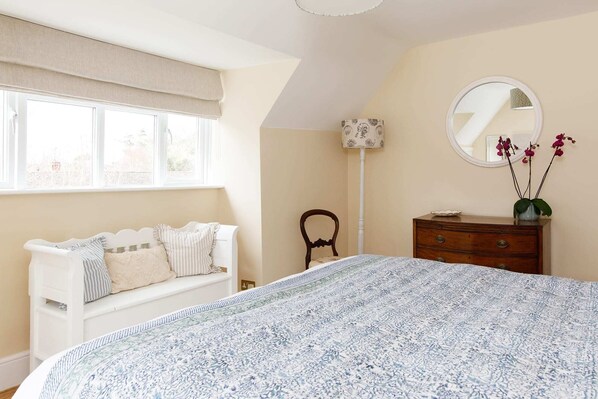 A bedroom with a large bed, a white sofa, a dresser, a mirror, and a window with a view. - Coastal Retreat in Picturesque Bosham (Bosham)