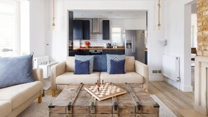 A modern living room with a sofa, coffee table, and a chessboard. - Coastal Retreat for 6 Close to Beaches (East Wittering)