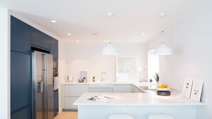 Una cocina moderna con una isla grande, electrodomésticos de acero inoxidable e iluminación colgante.