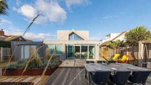 Una casa moderna con una amplia terraza, un comedor y un invernadero.