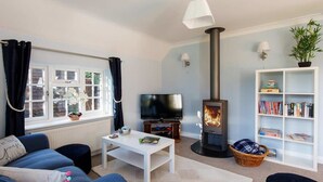 A cozy living room with a fireplace, a television, a bookshelf, and comfortable seating.