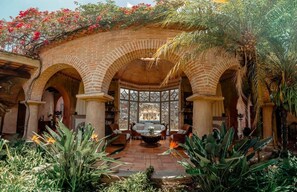 A courtyard with a central seating area, surrounded by brick arches and lush tropical plants. - Boutique Jazmin Stay, Pool in Antigua (Antigua Guatemala)
