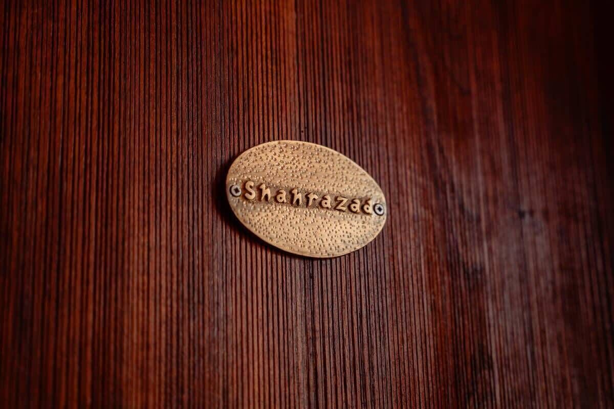 A wooden surface with a textured oval object that has the inscription "Shahrraz".