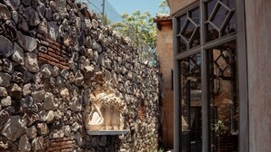 Una piscina con un muro de piedra y una estructura con ventanas.