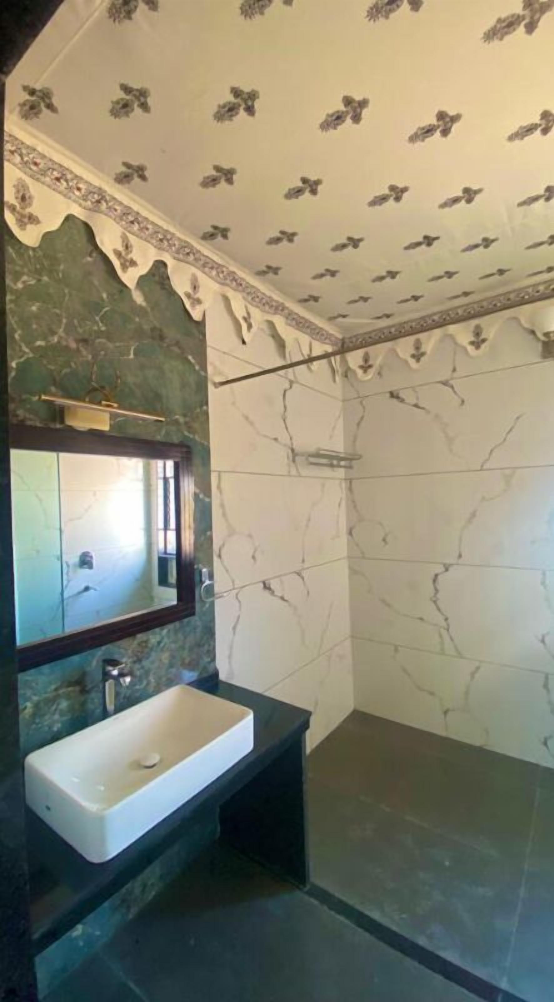A bathroom with a marble sink, a mirror, and a shower area.