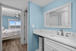 Enjoy a spacious bathroom with a double sink and large mirror, adjacent to a bedroom with a window offering a view of the sky.