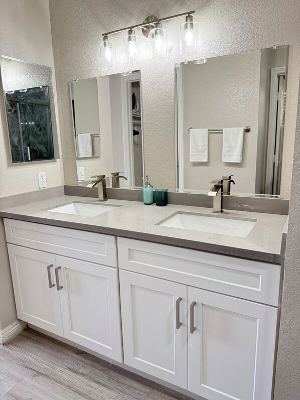 A bathroom with a double sink vanity, a large mirror, and a towel rack.