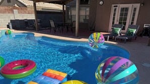 Une piscine avec des bouées gonflables et un ballon de plage.