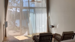 A bedroom with a large window, a bed, two chairs, a floor lamp, and a bedside table. - W181Ocean Stay (Geoje)