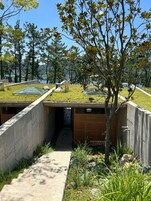 Un edificio moderno con techo plano, paredes de hormigón y un sendero que lleva a una puerta.