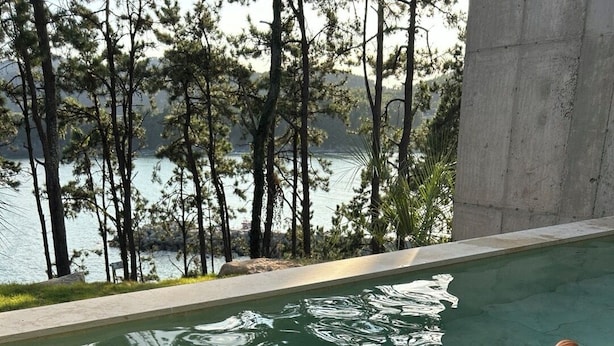 A poolside setting with a wicker basket containing a bottle and glasses, and a wooden deck. - W181Ocean Stay (Geoje)